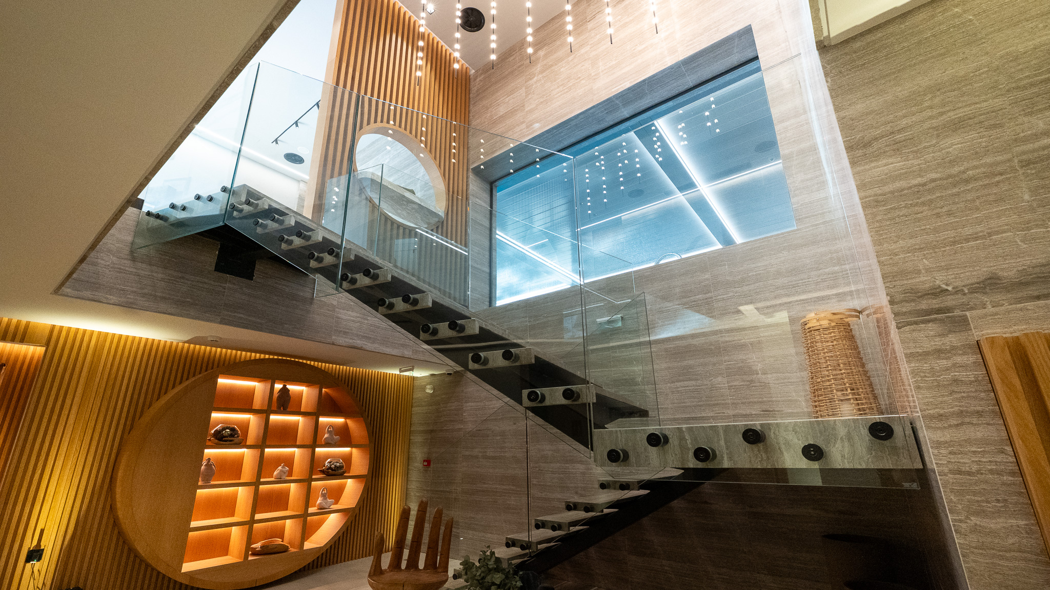 Dusit Suites Athens, wider lobby view of zigzag staircase against travertine wall