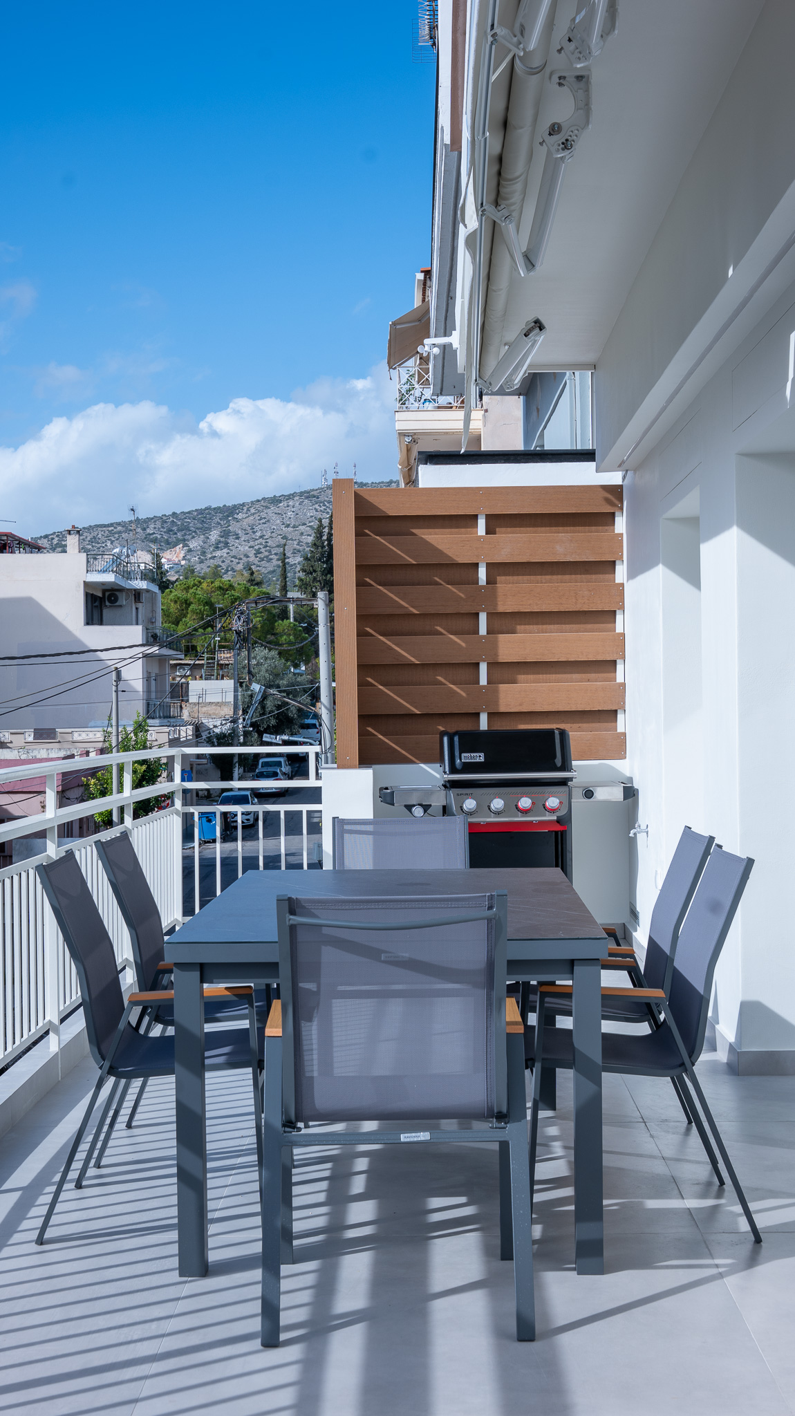 A&K Chorothetisis, balcony with grey dining set, BBQ and oak slat privacy screen against the hills