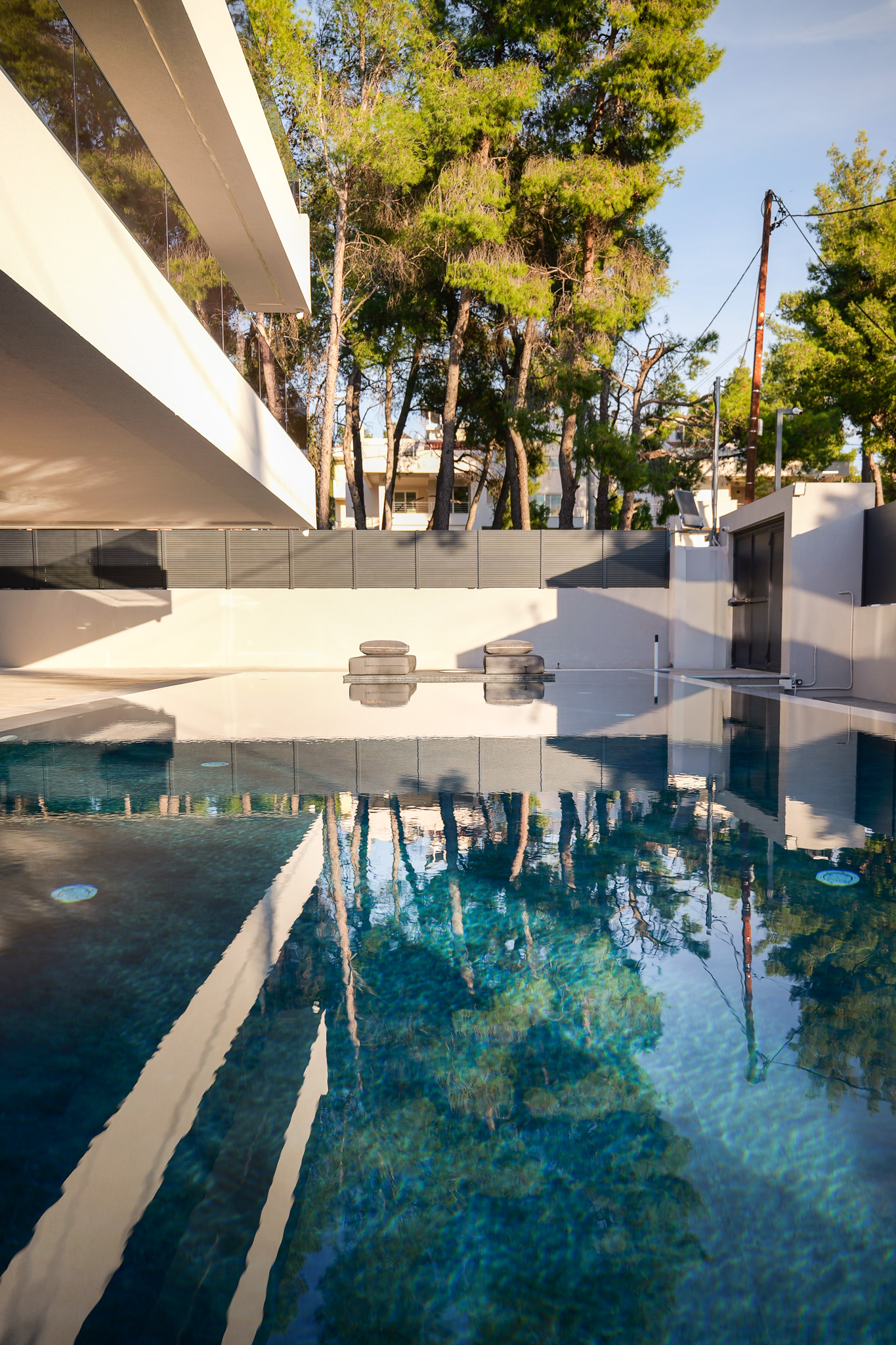 Villa Bond, pool with mirror-still water reflecting pines and white facade